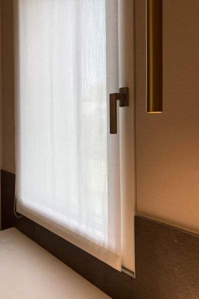 Particolare ferramenta e maniglia moderna su infisso in legno-alluminio di nuova costruzione a Noventa Vicentina. Soluzione d'arredo con integrazione tra serramento, tendaggio tecnico e rivestimento a parete scuro