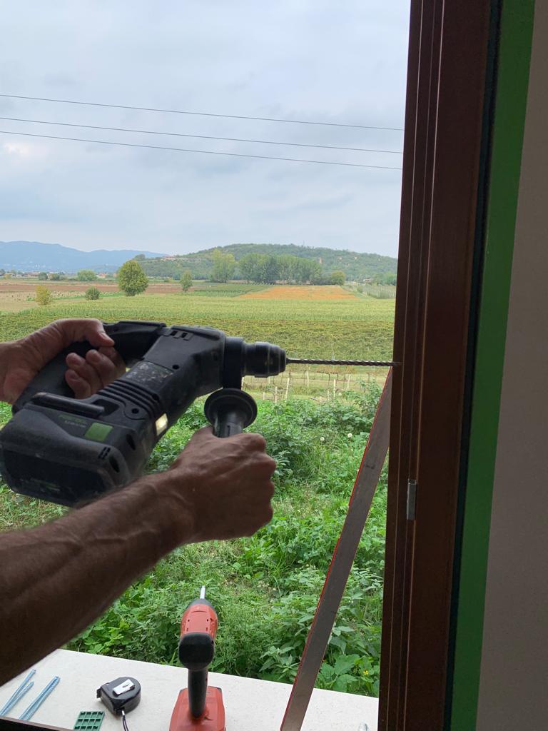 Installatore esegue il foro con tassellatore Festool sul telaio in legno per il fissaggio meccanico a parete.