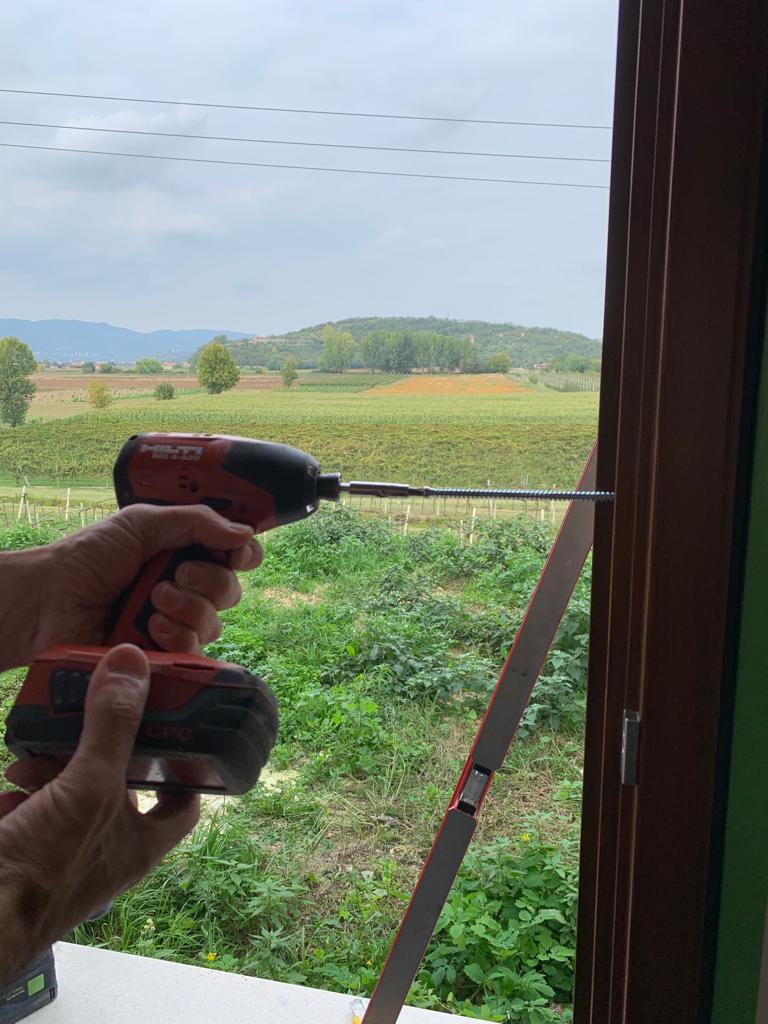 Fissaggio meccanico del telaio della finestra mediante avvitatore Hilti e vite autofilettante per calcestruzzo.
