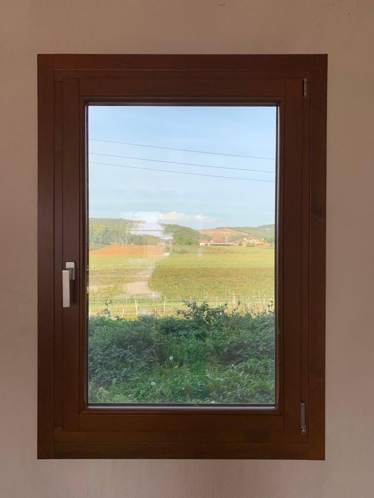 Posa in opera completata di una finestra in legno con vista panoramica sulle colline, lavoro finito e pulito