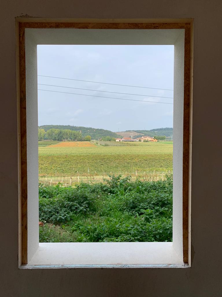Controtelaio coibentato per finestra ad alta efficienza energetica con vista su panorama collinare.