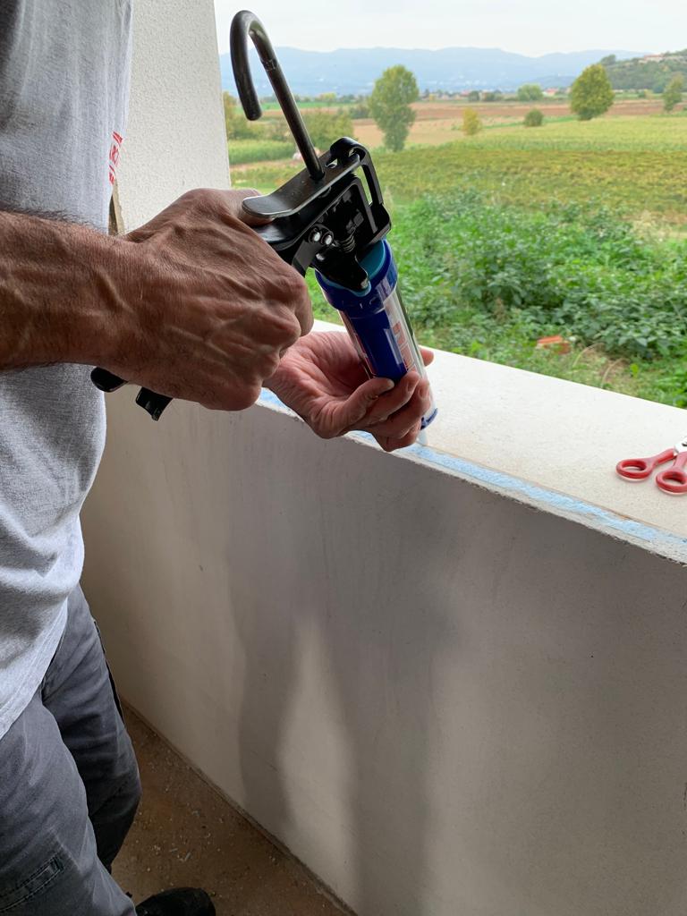 Artigiano applica sigillante fluido sul quarto lato del foro finestra per garantire l'impermeabilizzazione.